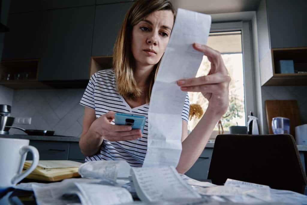 high ticket affiliate marketing. woman looking at bills calculating how much money she has left over